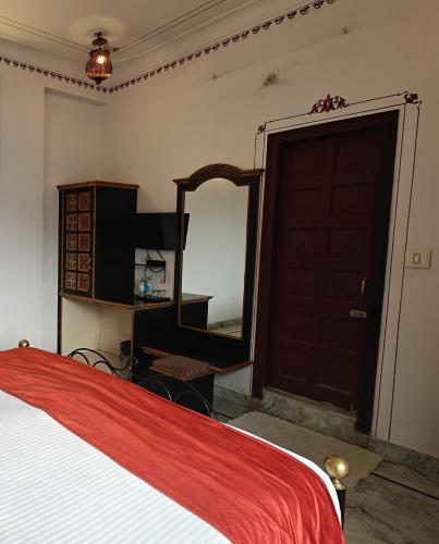 a bedroom with a bed and a mirror and a dresser at Baba Palace - A Heritage Hotel, Udaipur in Udaipur