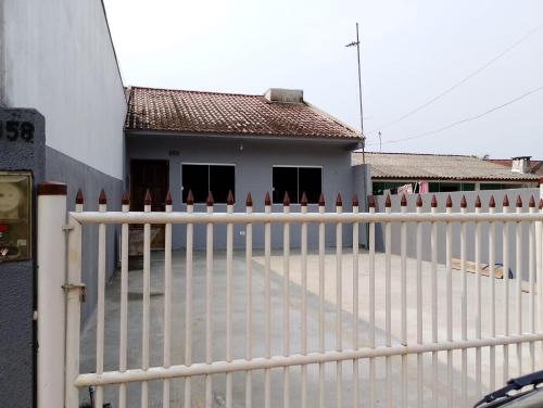 a white fence in front of a house at Casa F Pontal do Paraná in Pontal do Paraná