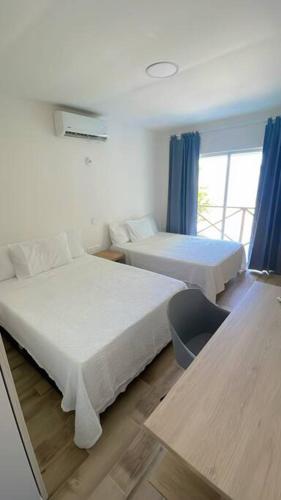 een hotelkamer met twee bedden en een raam bij Casa Mar in Puerto Colombia