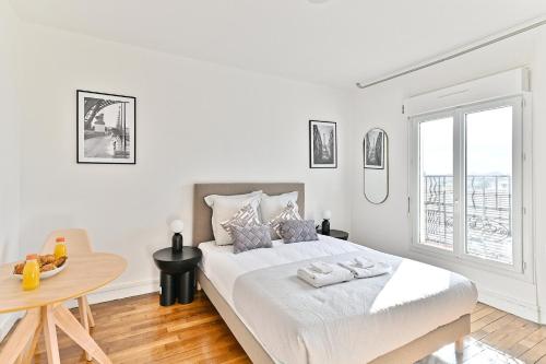 une chambre blanche avec un grand lit et une table dans l'établissement Studio confortable Havre de Paix proche Paris - II, à Montreuil