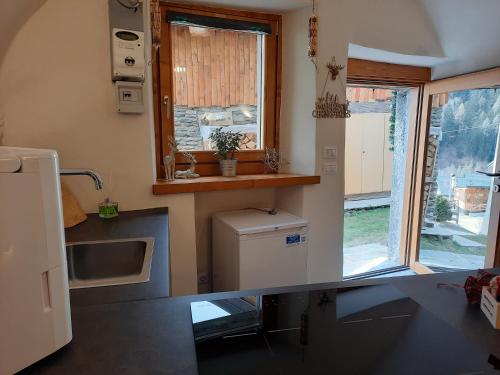małą kuchnię ze zlewem i oknem w obiekcie Chalet Sweet Mountain w mieście Ponte di Legno