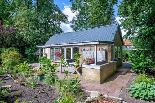 a tiny house in a garden with a greenhouse at Landhuisje 31 'De Akkersteen' Bospark IJsselheide Zwolle Hattemerbroek in Hattemerbroek