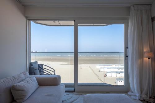 a living room with a couch and a view of the beach at Volledig gerenoveerd 2 slaapkamer appartement met zeezicht! in Knokke-Heist