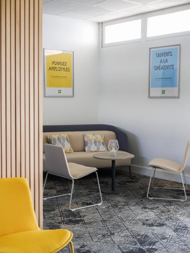 a waiting room with a couch and chairs at ibis Styles Poitiers Nord in Poitiers