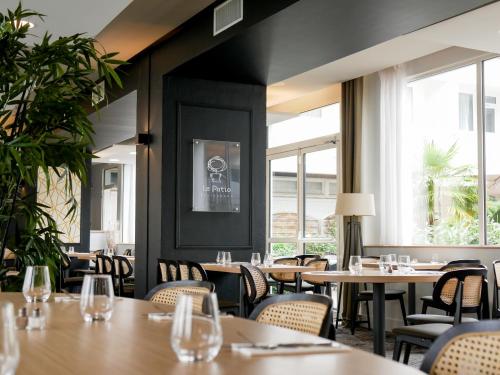 a restaurant with tables and chairs and windows at ibis Styles Poitiers Nord in Poitiers