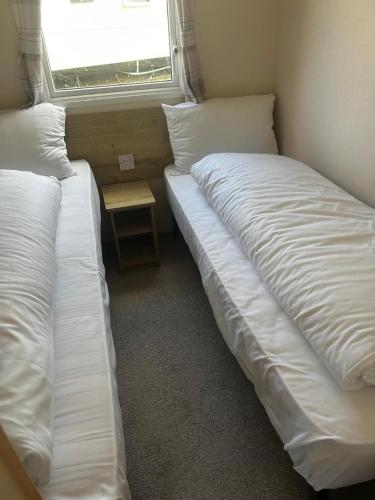 two twin beds in a room with a window at Perranporth Coastal Retreat- Sleeps8 in Perranporth