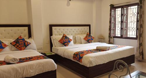 a bedroom with two beds and two windows at Baba Palace - A Heritage Hotel, Udaipur in Udaipur