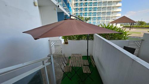 a table and chairs under an umbrella on a balcony at Hailey's Crib @ Azure North in San Fernando