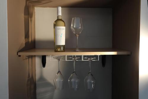 a bottle of wine and wine glasses on a shelf at Suite Monopoli in Monopoli