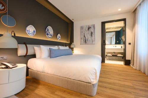 a bedroom with a large white bed and blue plates on the wall at Fletcher Hotel-Restaurant Oisterwijk-Tilburg in Oisterwijk