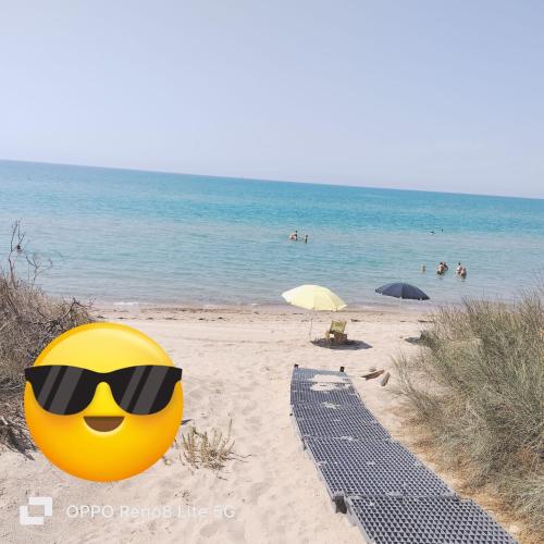 a yellow smiley emoticon wearing sunglasses on a beach at A Casa Mia in Butera