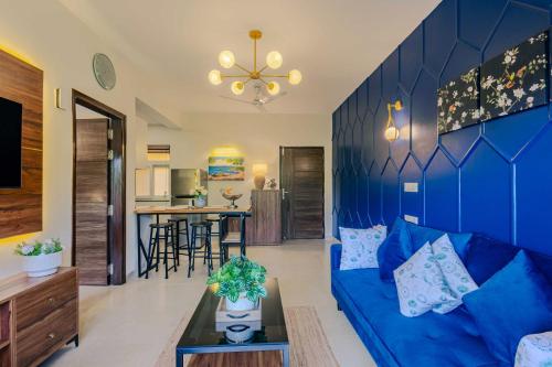 a living room with a blue couch and a table at Alaya Stays 1 BHK with Balcony & Pool - Veera Marina in Goa