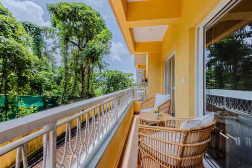 a balcony with chairs and a table and a view of trees at Alaya Stays 1 BHK with Balcony & Pool - Veera Marina in Goa