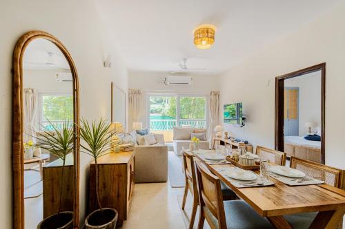 a dining room with a table and a living room at Alaya Stays 1 BHK with Balcony & Pool - Veera Marina in Goa