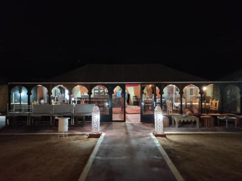 a tent with a table and chairs in the dark at Oasis Luxury Camp in Merzouga