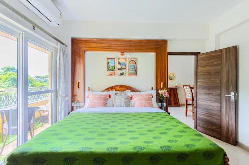 a bedroom with a large bed with a green blanket at Alaya Stays 1 BHK with Balcony & Pool - Veera Marina in Goa