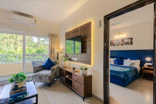 a bedroom with a bed and a chair and a window at Alaya Stays 1 BHK with Balcony & Pool - Veera Marina in Goa