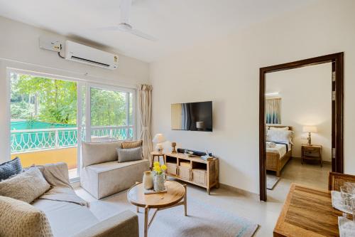a living room with a couch and a table at Alaya Stays 1 BHK with Balcony & Pool - Veera Marina in Goa