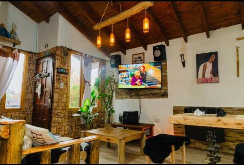 a living room with a table and a tv on the wall at Cabaña Onty in El Calafate