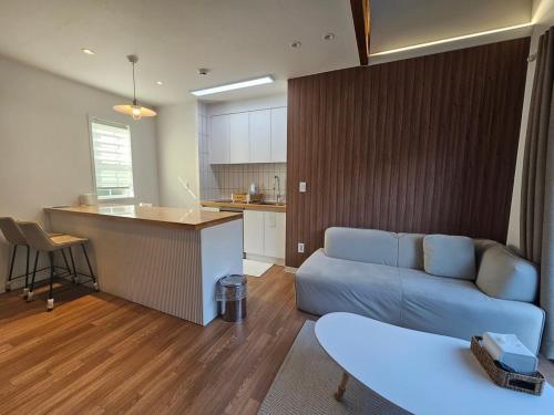 a living room with a couch and a kitchen at Danyang Kotdle Moolgam Chatki Pension in Danyang