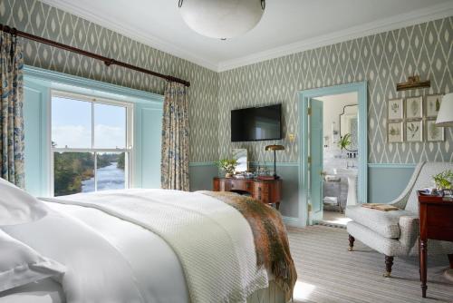 a bedroom with a bed and a chair and a window at Ballynahinch Castle Hotel in Ballynahinch