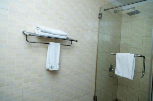 a bathroom with a shower and towels on a wall at The Country Inn Hotel in Kigali