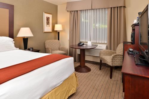 a hotel room with a bed and a table and chairs at Holiday Inn Express Portland South - Lake Oswego by IHG in Lake Oswego