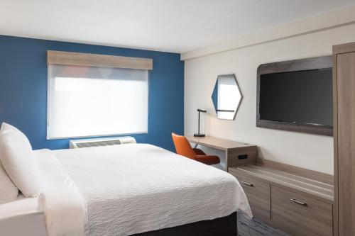 a hotel room with a bed and a flat screen tv at Holiday Inn Express Portland South - Lake Oswego by IHG in Lake Oswego