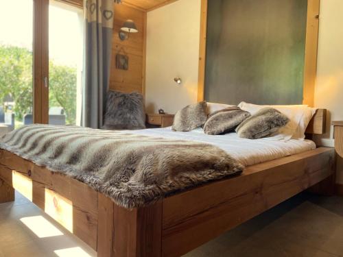 a bedroom with a large wooden bed with a large window at Chambres à la ferme au pied des pistes de Megève in Demi-Quartier