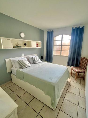 a bedroom with a bed with blue curtains and a chair at Apartamentos até 6 pessoas - 3 quartos, suíte, garagem e wifi in Piracicaba