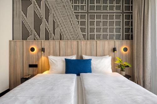 a bedroom with two beds and a wall with a blue pillow at Citadines Kurfürstendamm Berlin in Berlin