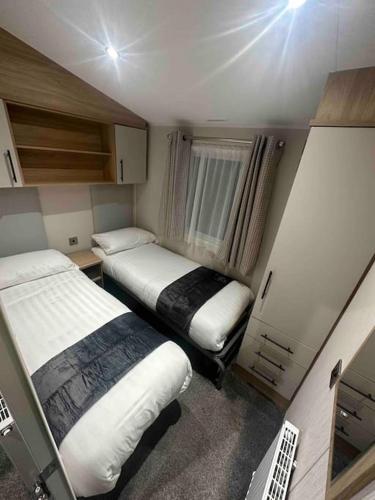 a small room with two beds and a window at BRAND NEW 8 berth holiday home in Selsey