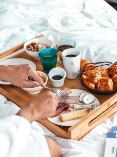 - un plateau de produits pour le petit-déjeuner sur un lit dans l'établissement L'Ermitage Hôtel Cuisine-À-Manger, à Saint-Cyr-au-Mont-dʼOr