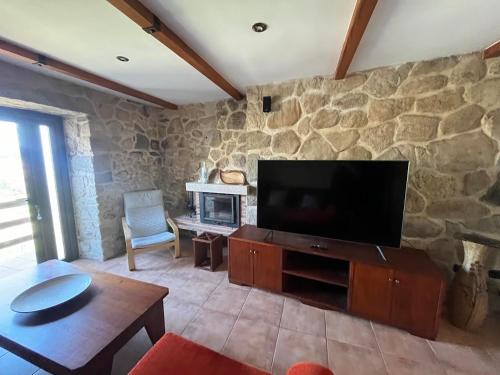 a living room with a tv and a stone wall at Casa Dantes in Oia