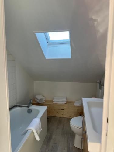a bathroom with a tub and a toilet and a skylight at Studio fécamp in Fécamp