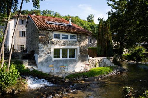 a stone house with two chairs next to a river at Belle grange en bord de rivière in Serres-sur-Arget