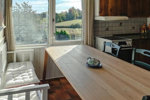 a kitchen with a wooden table and two windows at Det huset på landet in Nøtterøy