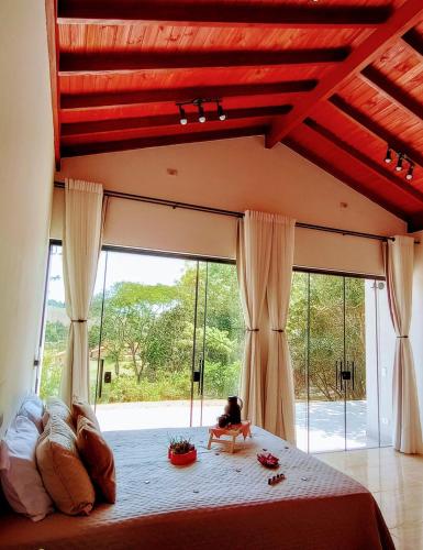 a bedroom with a large bed and a large window at Cabanas Privativas com Jacuzzi, Cozinha, Churrasqueira e Decoração - Sitio Pauletto in Jarinu