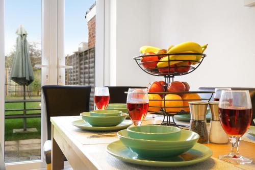 a table with a bowl of fruit and glasses of wine at Three bedroom house for your family and workstays in Amersham