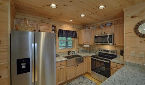 a kitchen with a stainless steel refrigerator and wooden cabinets at Experience Luxury and Serenity at 3 Little Bears Just Minutes from Top Attractions Private Indoor Pool Hot Tub in Pigeon Forge