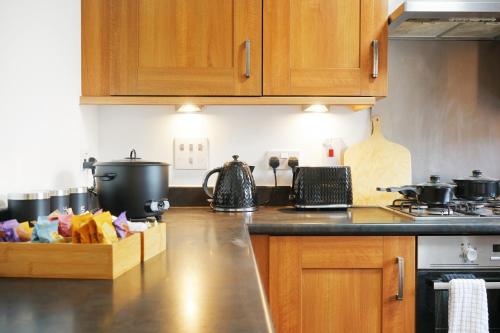 a kitchen with wooden cabinets and a counter top at Three bedroom house for your family and workstays in Amersham