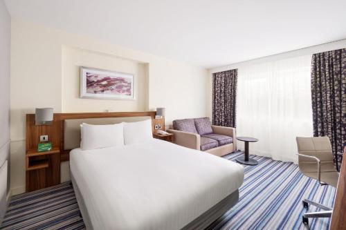 a hotel room with a bed and a chair at Holiday Inn Colchester by IHG in Colchester