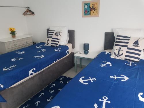 - une chambre avec 2 lits avec des draps blancs et bleus dans l'établissement Nautilus Joli T3 Appartement Terrasse Climatisation, à Sète