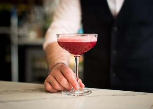a person holding a glass with a pink drink at voco Grand Central Glasgow by IHG in Glasgow