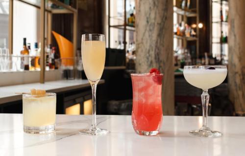 three cocktails sitting on a table in a bar at voco Grand Central Glasgow by IHG in Glasgow