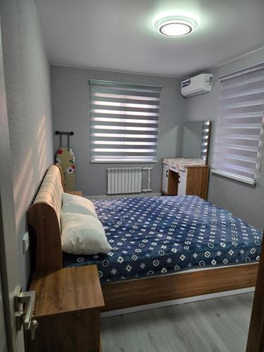 a bedroom with a bed in a room with windows at Новая квартира в 10 минутах от центра города in Qŭyliq
