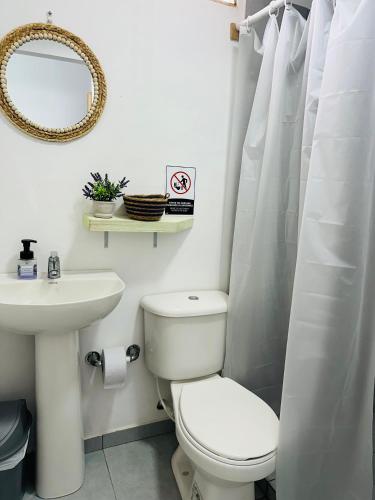 a white bathroom with a toilet and a sink at Itaca Eco House in Playa Blanca