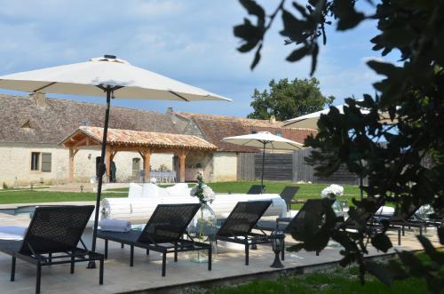 a group of chairs and a table with an umbrella at Le Murmure des Fées in Issigeac