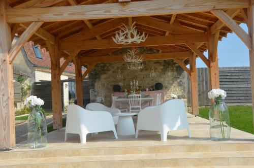 a wooden pavilion with white chairs and a table at Le Murmure des Fées in Issigeac