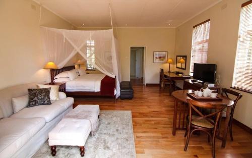 a bedroom with a bed and a living room with a couch at Chic studio nestled in lovely garden and pool-2254 in Harare